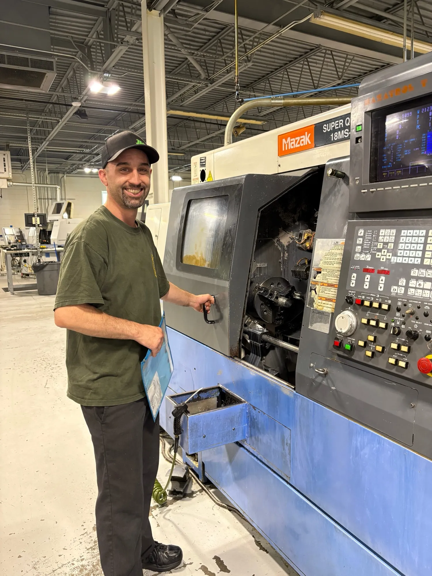 A CNC Manufacturing machinist at a Mazak CNC lathe on the production floor